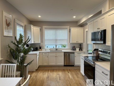 A kitchen with white cabinets and a wooden floor.