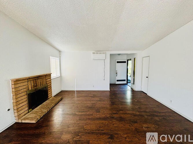 A living room with a fireplace and wood flooring.