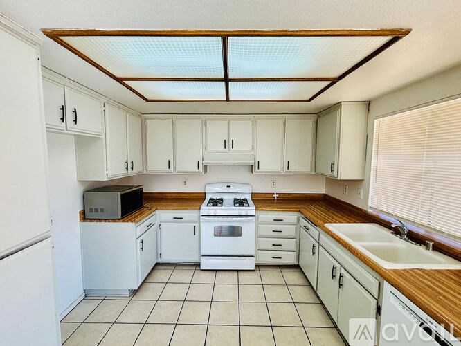 A kitchen with white cabinets and a white stove top oven.