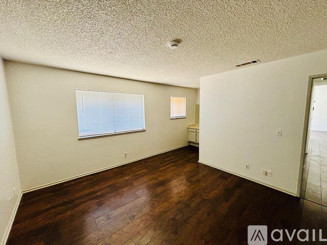 A room with wooden floors and a window with blinds.