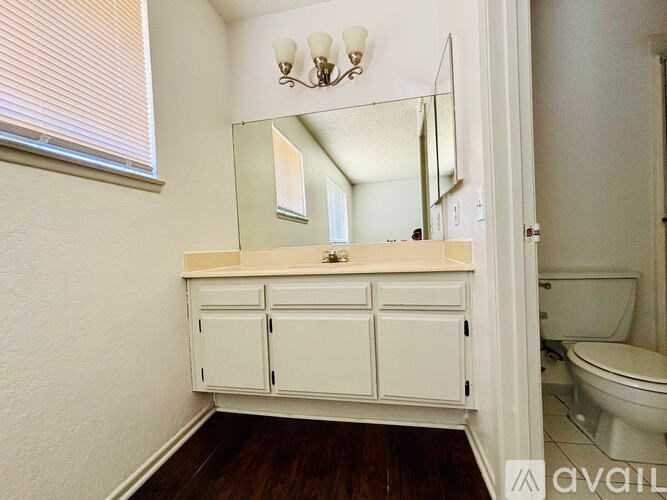 A bathroom with a white cabinet and a mirror above it.