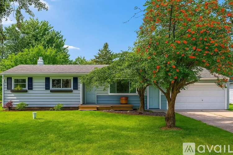 A house with a blue exterior and a tree with orange flowers in front.