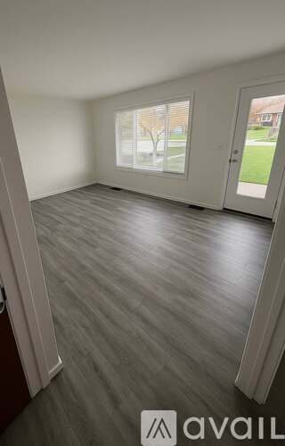 A room with wooden flooring and a window overlooking a green lawn.