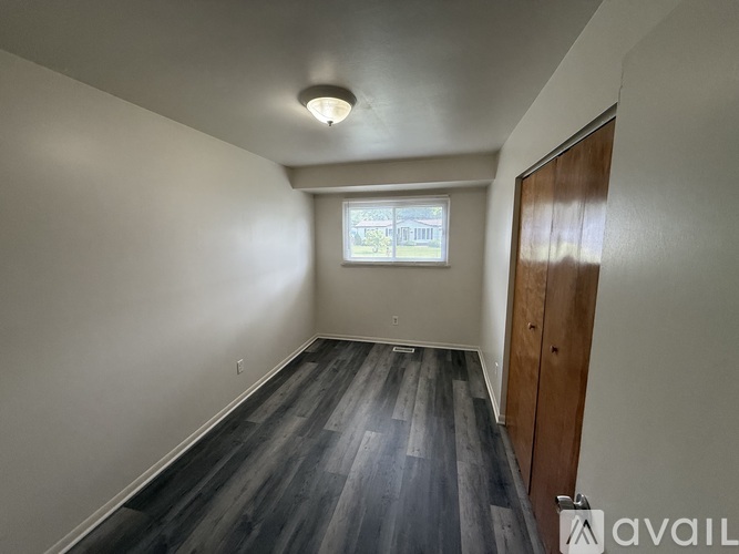 A room with wooden flooring and a window with blinds.