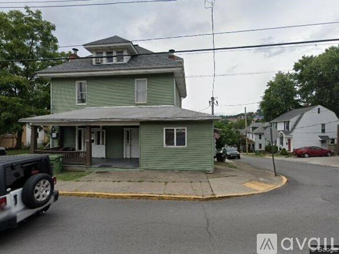 A green house with a white car parked in front.