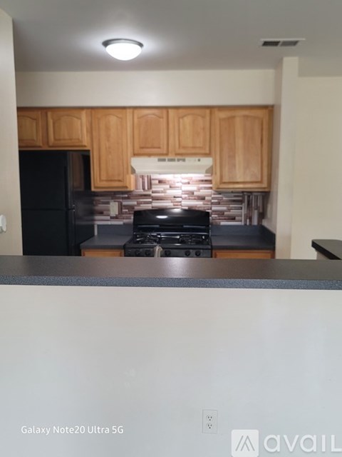 A kitchen with wooden cabinets and a black refrigerator.