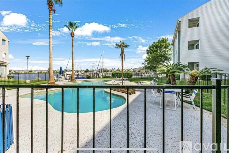 A pool surrounded by a fence with palm trees in the background.