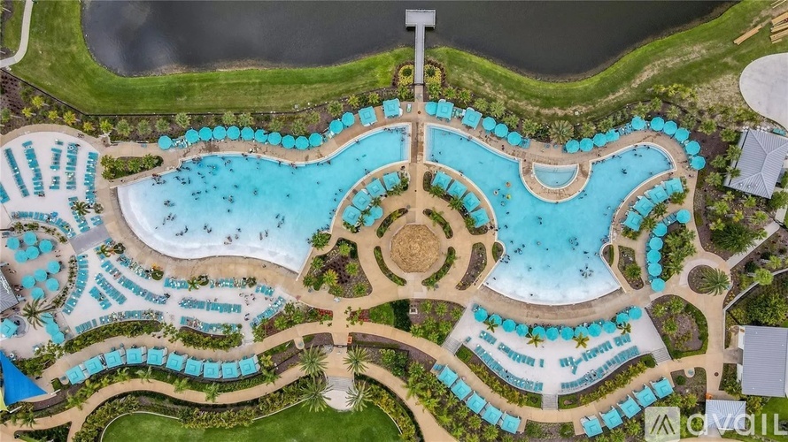 An aerial view of a resort with a large swimming pool and surrounding cabanas.