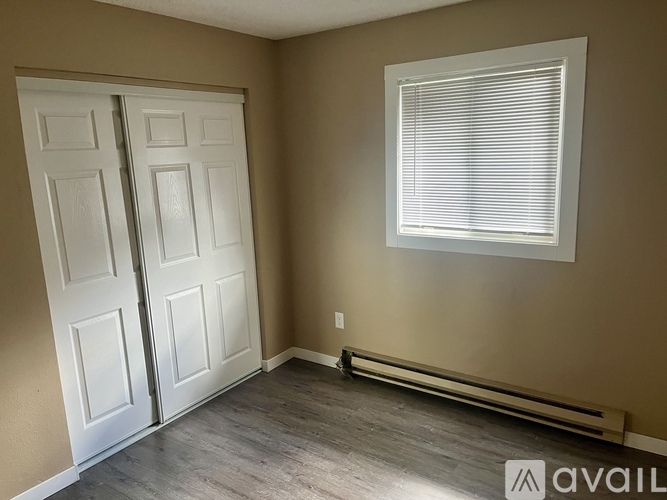 A room with a white door and a window with blinds.