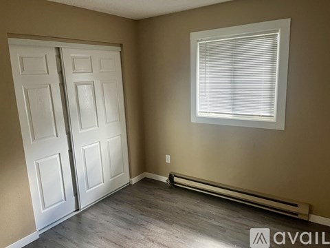 A room with a white door and a window with blinds.