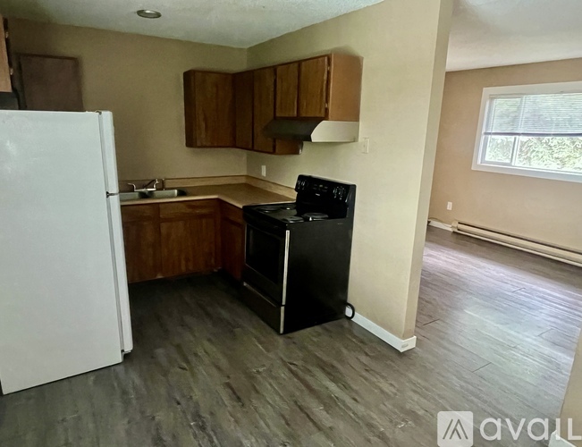 A kitchen with a white refrigerator, wooden cabinets, and a black stove top oven.