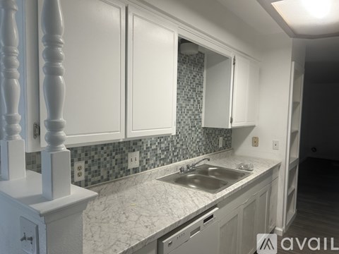 A kitchen with white cabinets and a marble countertop.