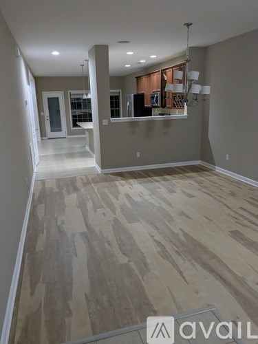 A room with wooden flooring and a bar area in the background.