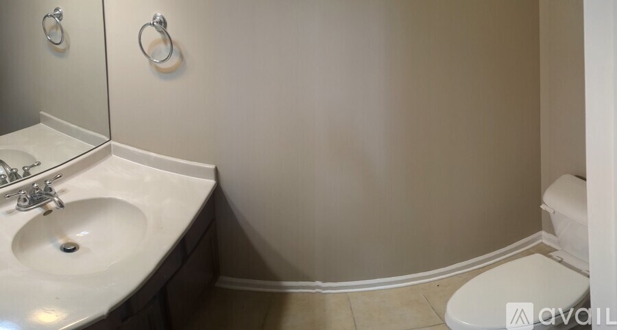 A bathroom with a toilet, sink, and mirror.