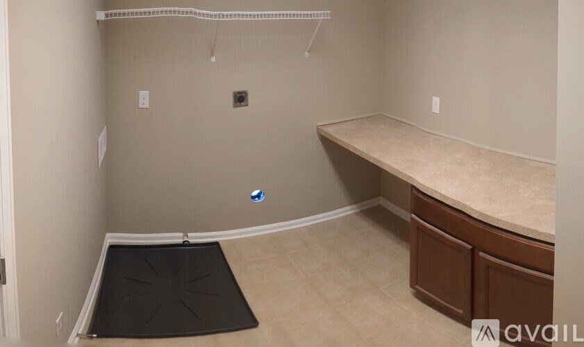 A room with a desk and a black mat on the floor.