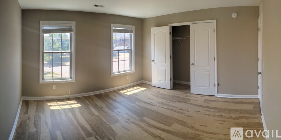 A room with wooden floors and two windows.