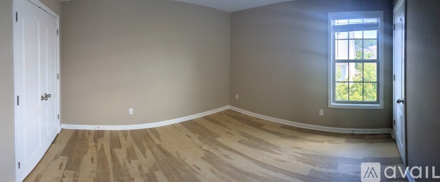 A room with a window and wooden flooring is available for rent.