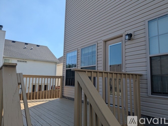 A wooden deck with a railing and a window on a building.