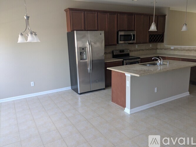 A kitchen with a refrigerator, microwave, and oven.