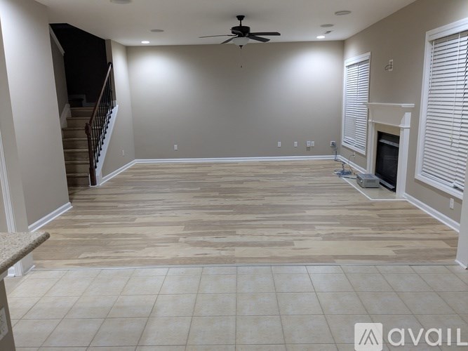 A spacious living room with a fireplace and a staircase.