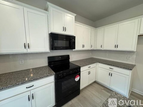 A kitchen with white cabinets and black appliances.