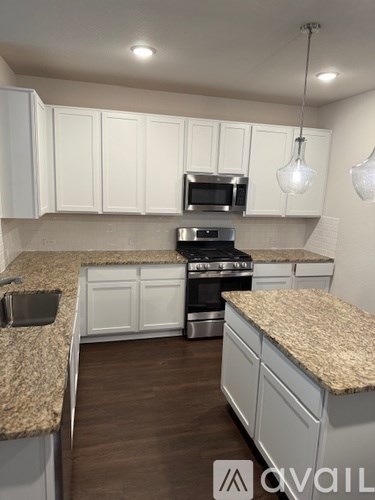 A kitchen with granite countertops and white cabinets.