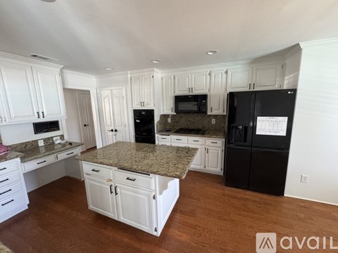 A kitchen with white cabinets and a black fridge.