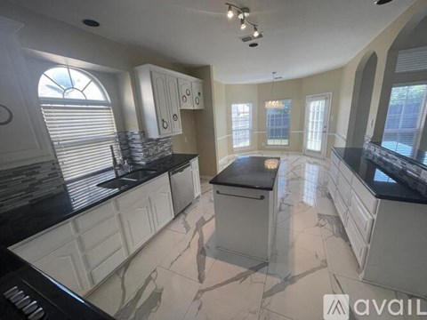 A kitchen with white cabinets and black countertops.