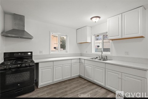 A kitchen with white cabinets and a black stove top oven.