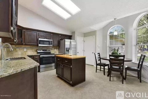 A kitchen with brown cabinets and a marble countertop.