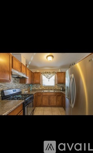 A kitchen with wooden cabinets and a stainless steel refrigerator.