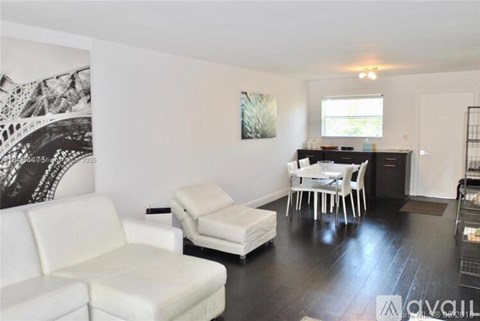A living room with a white couch and a black and white artwork on the wall.