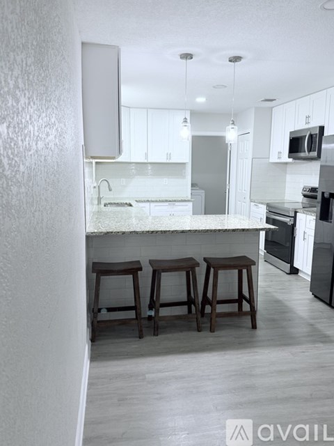 A kitchen with white cabinets and a bar area with stools.