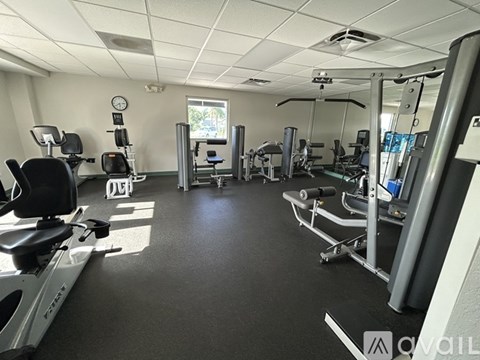 A gym with various exercise machines and a clock on the wall.