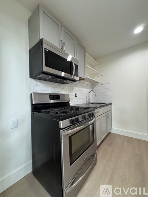 A kitchen with a black stove top oven and a black microwave above it.