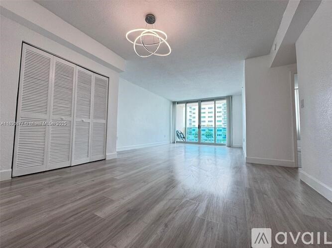 A room with wooden flooring and a large window with a view of a building outside.