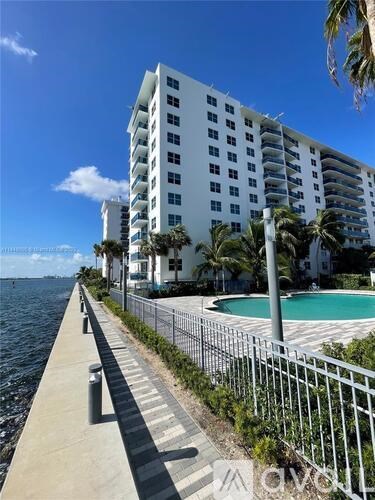 A white building with a pool and palm trees in front.