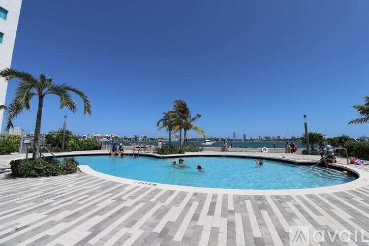 A swimming pool with people in it and palm trees around it.