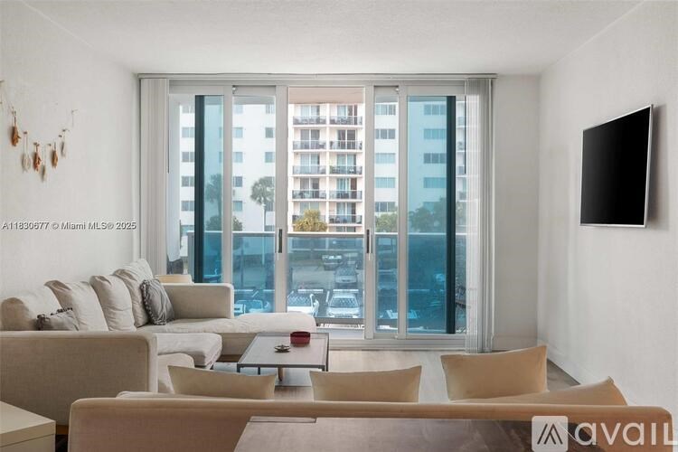 A living room with a large window overlooking a parking lot.