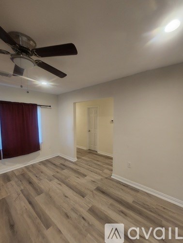 A room with a ceiling fan and wooden flooring.