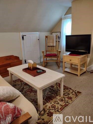 A living room with a white coffee table and a television on a wooden stand.