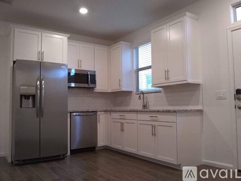 A kitchen with white cabinets and a stainless steel refrigerator.
