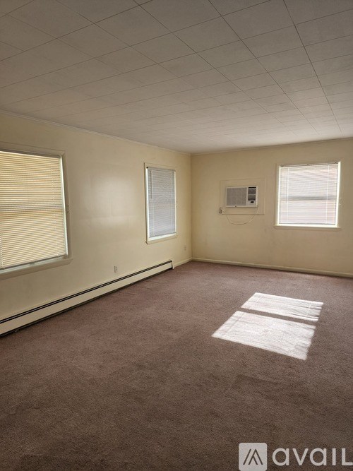 A room with a carpeted floor and a window with blinds.