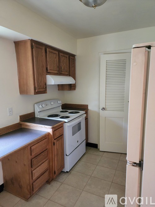 A kitchen with wooden cabinets and a white stove top oven.