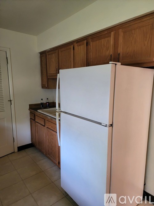 A white refrigerator in a kitchen with wooden cabinets.