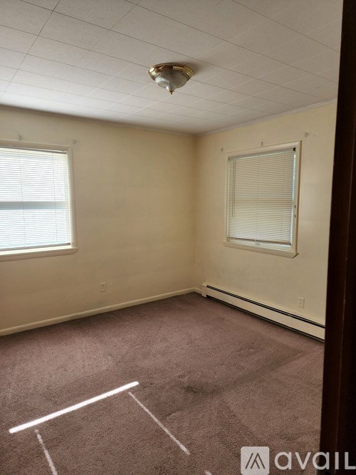 A room with a carpeted floor and a window with blinds.