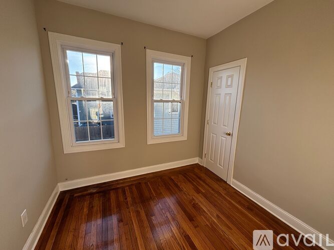A room with wooden floors and two windows.