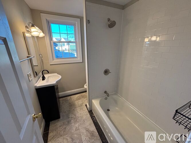 A bathroom with a tub, sink, and window.