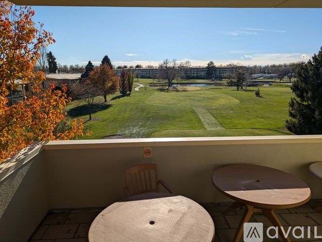 A balcony with a table and chairs overlooking a grassy field and trees.