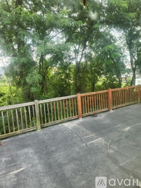 A wooden fence on a concrete surface with trees in the background.